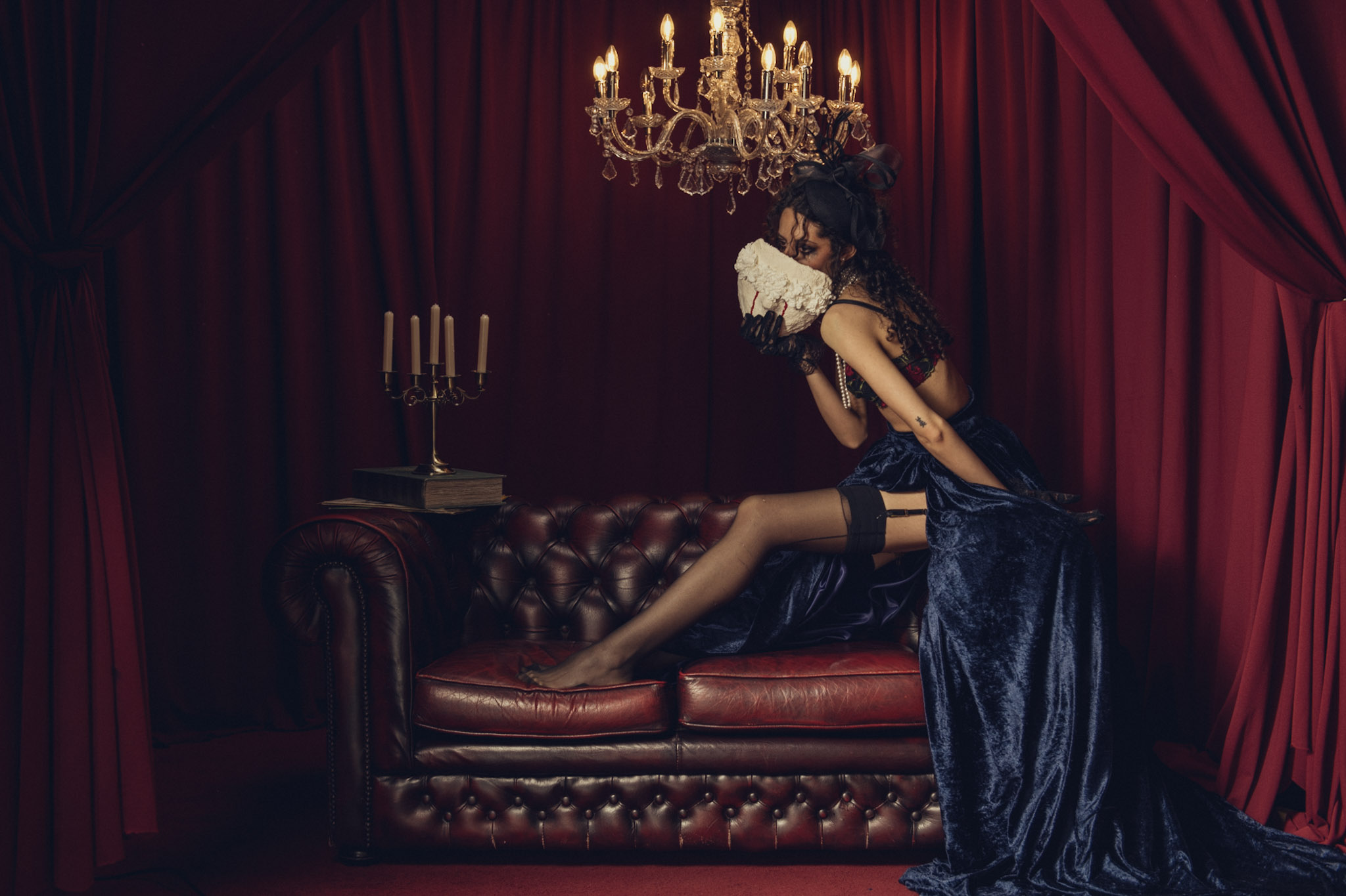 Dark Baroque staged fashion portrait with blue satin and ivory floral prop