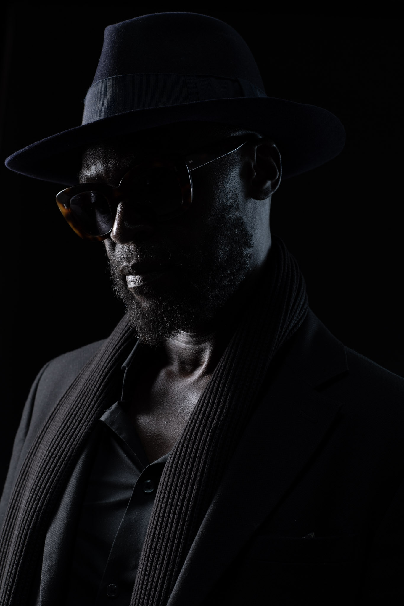 Close portrait of Kyazi Lugangira in a black hat and sunglasses