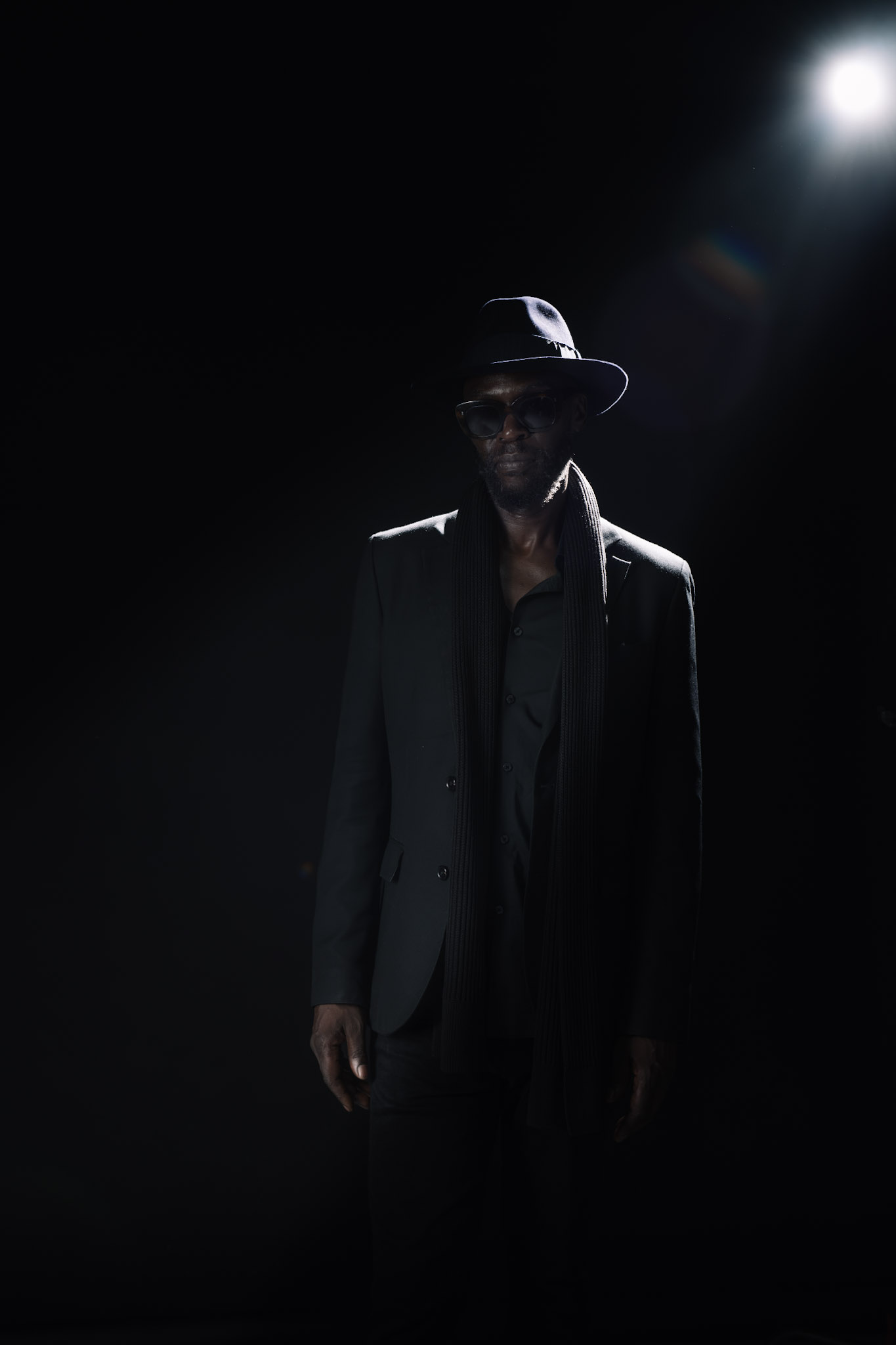 Full-length portrait of Kyazi Lugangira beneath a bright studio light
