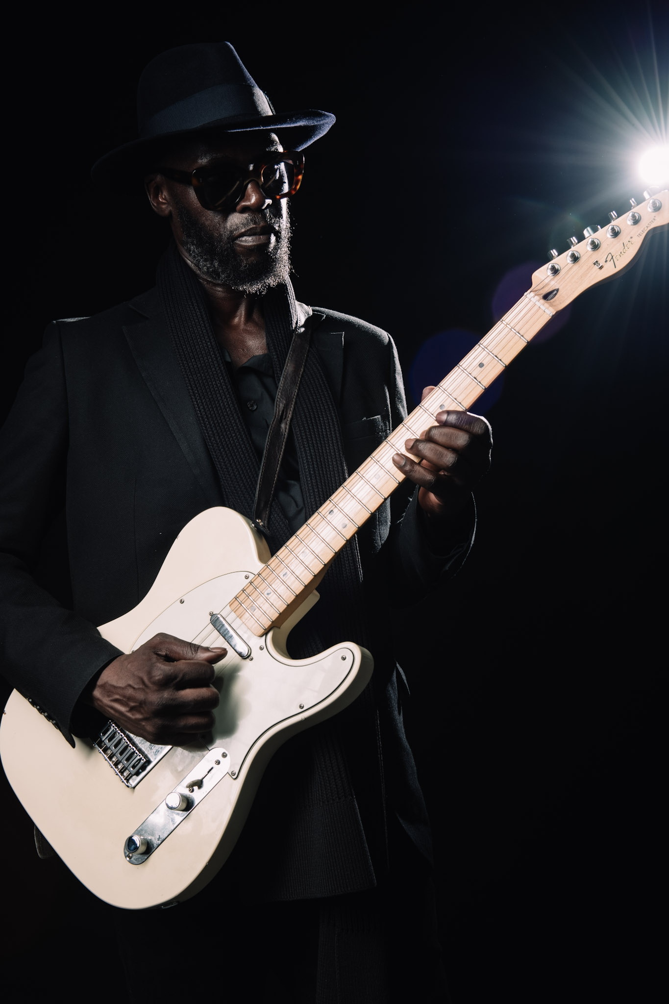 Kyazi Lugangira with a white Fender Telecaster in dramatic rim light