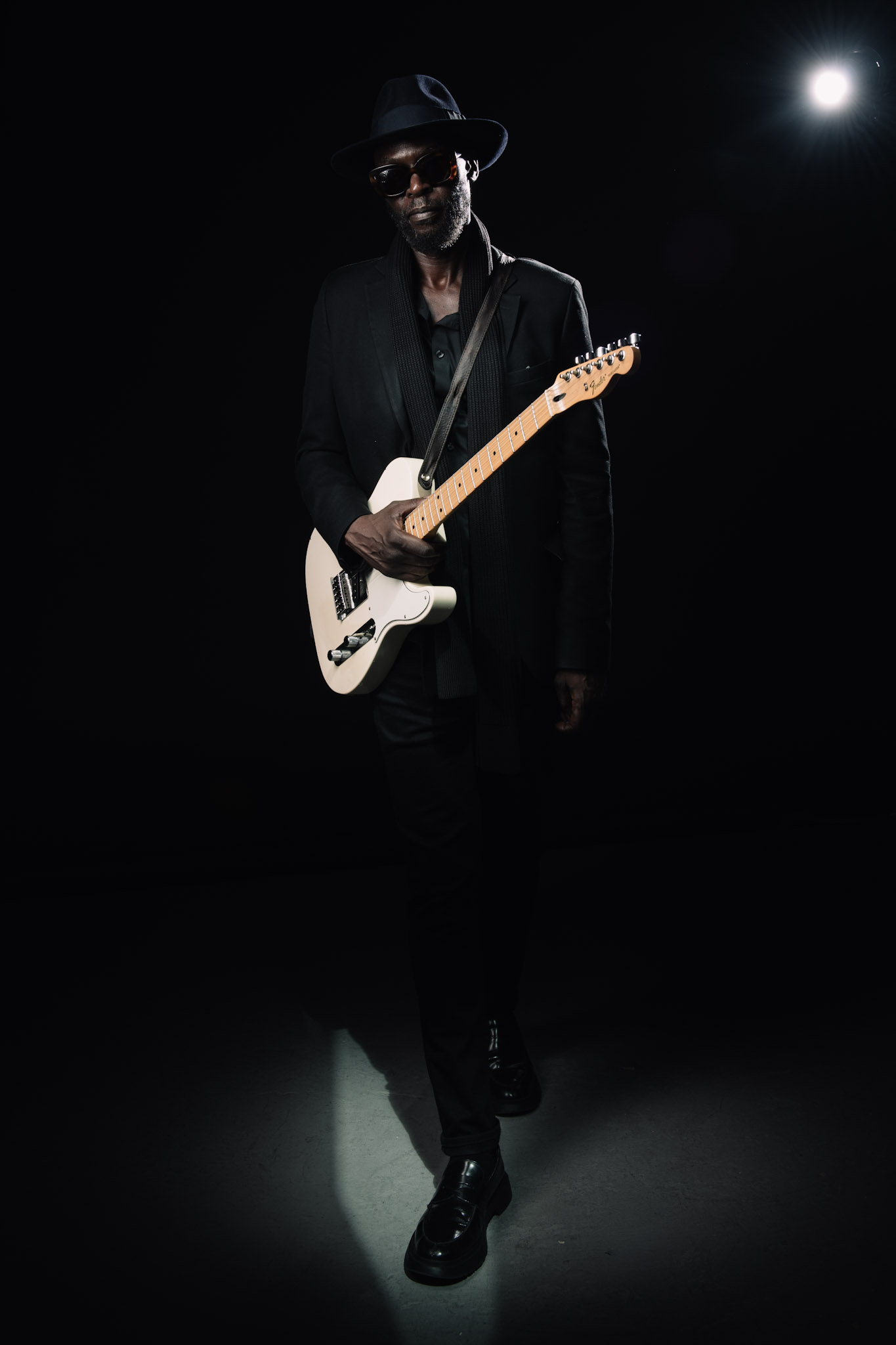 Full-length portrait of Kyazi Lugangira with a white electric guitar