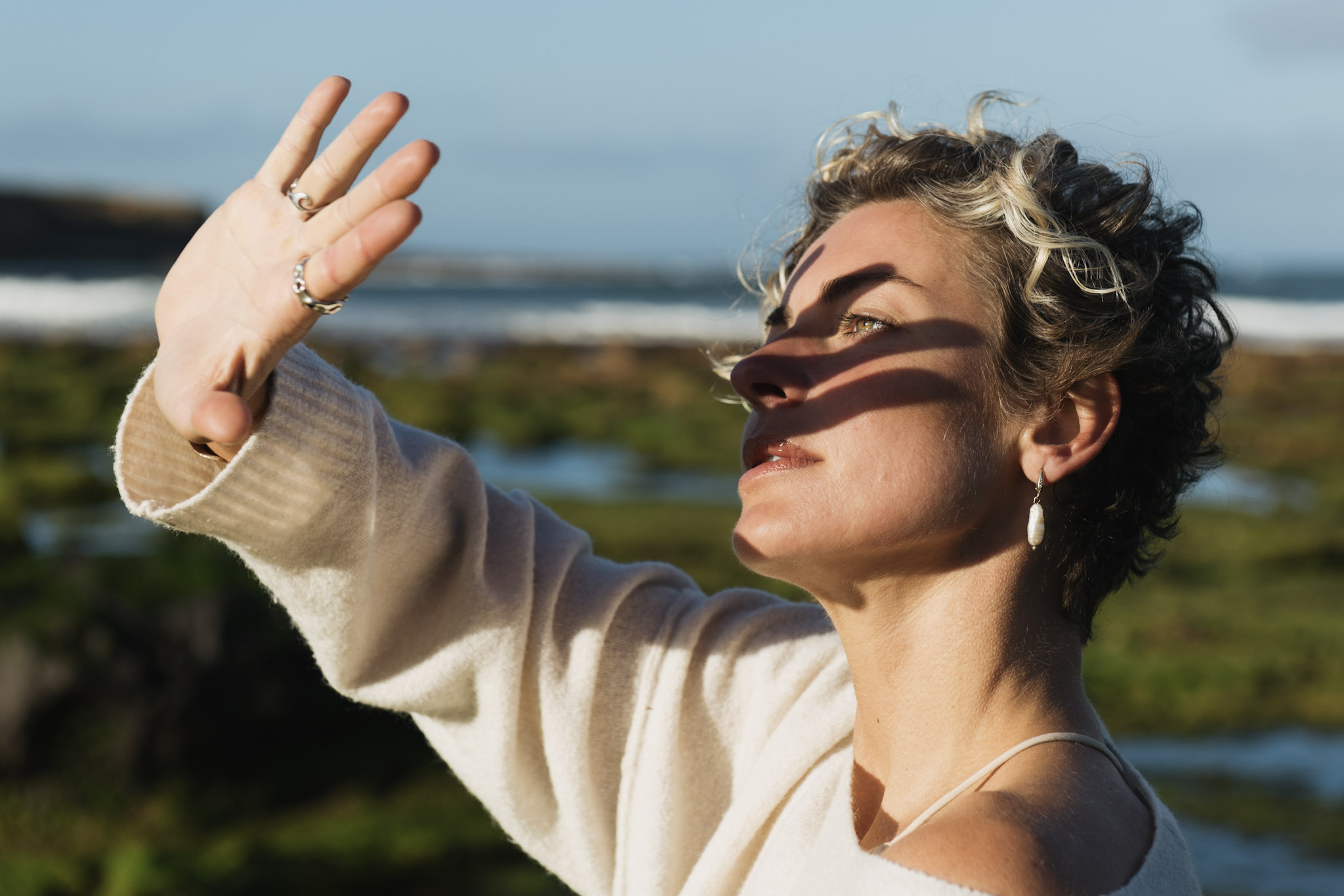 Close coastal portrait of a woman shading her eyes in warm sunlight
