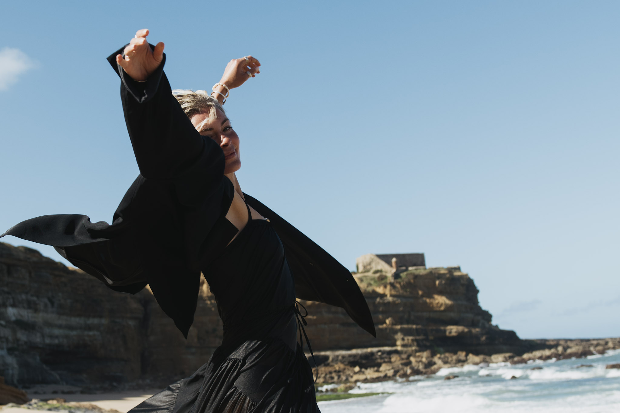 Close movement portrait of a woman in a black dress beside Atlantic surf
